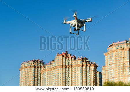 Drone quad copter with onboard high resolution digital camera flying over the city in the blue sky