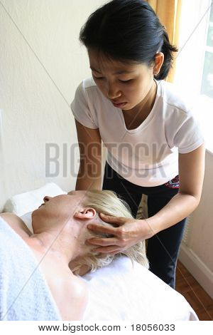 Un massaggiatore signora dando un massaggio alla testa al suo cliente. (Adatto per immagine spa)
