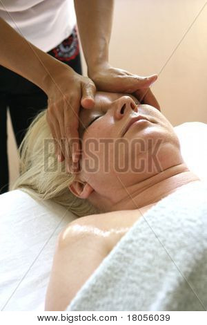 Un massaggiatore signora dando un massaggio alla testa al suo cliente. (Adatto per immagine spa)