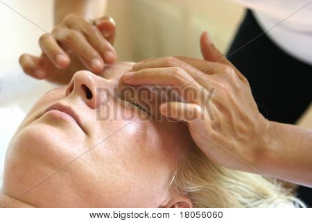 Un massaggiatore trattando il suo cliente con massaggio olistico del viso