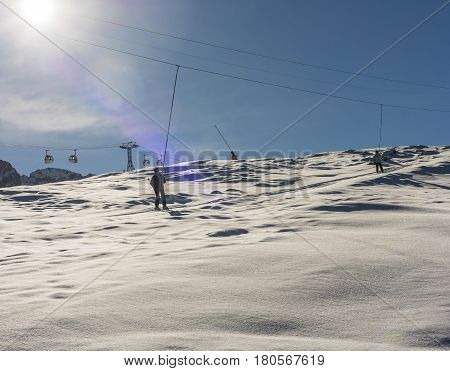 Skier on a ski lift piste in snowy winter alpine mountain resort