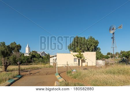 PHILIPPOLIS SOUTH AFRICA - MARCH 21 2017: A street scene with a house windmill and the Dutch Reformed Church in Philippolis the oldest town in the Free State Province