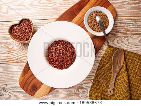 Red wild rice with sesame gomasio seasoning in a white plate over wooden board
