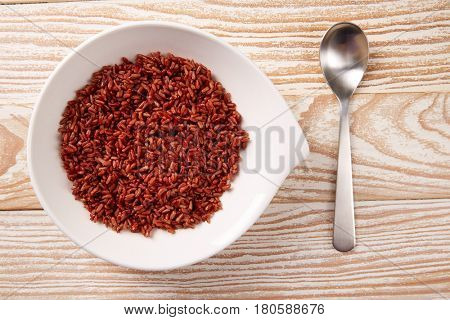 Red wild rice in a white plate over wooden board