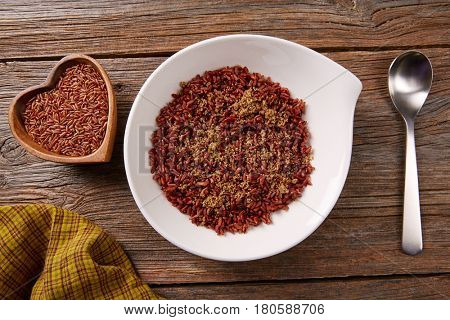 Red wild rice in a white plate over wooden board