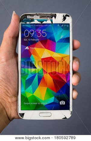 Chiangrai Thailand: March 17 2017 - Human hand holding broken Samsung Note2 smartphone and showing colorful lock screen