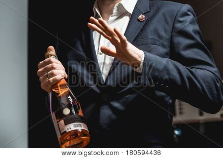 Sommelier in a dark blue jacket holding a bottle of wine and tells the audience about the various wines.