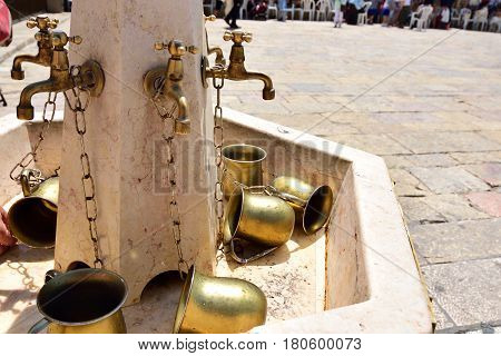 Water standpipe and copper pots for ritual ablution on square near Wailing Wall in Jerusalem.