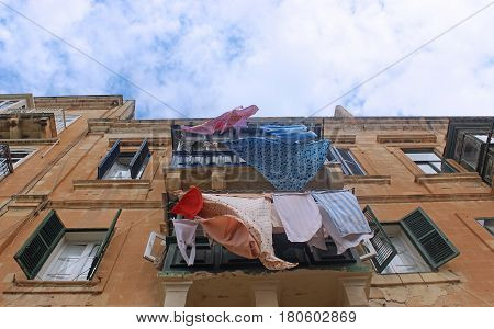 colorful clothes hanging on the line outside a balcony sandstone house with shutters view up into the sky