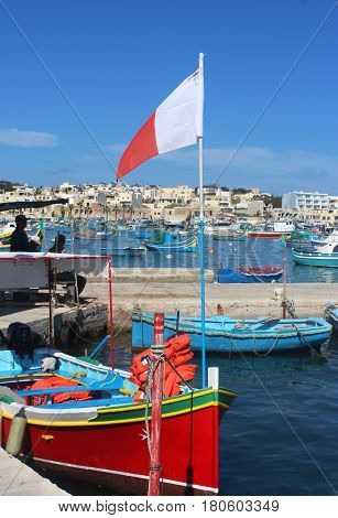 colorful traditional fishing boat with Maltese flag in Marsaxlokk Malta a fishers village