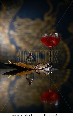 Fresh branded red alcoholic cocktail with a small bottle for alcohol and a red marmalade snack on a black stone bar counter. Concept of alcoholic and non-alcoholic bar beverage.