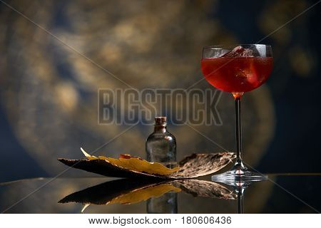 Fresh branded red alcoholic cocktail with a small bottle for alcohol and a red marmalade snack on a black stone bar counter. Concept of alcoholic and non-alcoholic bar beverage.