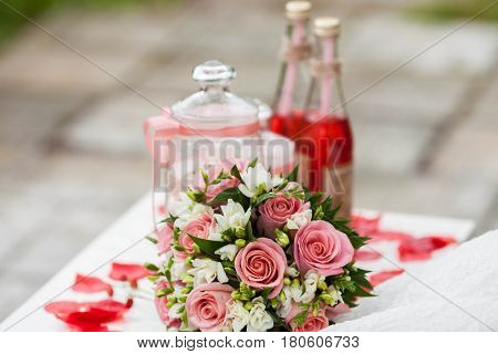 Delicate bride's bouquet on the table next to red lemonade .