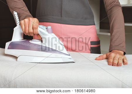 Young woman in uniform with steam iron