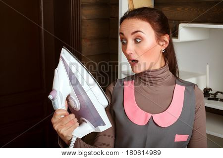 Surprised woman looking at the sole of the iron