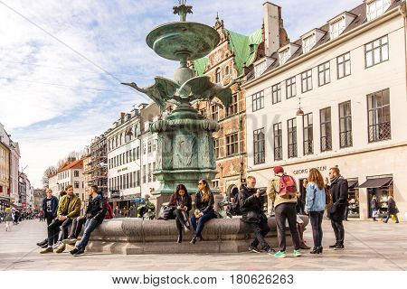 The Stork Fountain with young people sitting on the edge. Amagertorv in central Copenhagen Denmark - Mars 23 2017