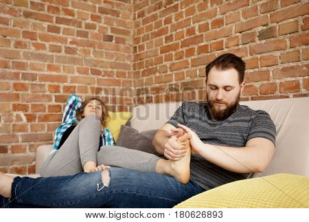 Man is massaging woman's foot, in home.