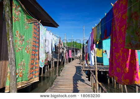 Colorful lavaggio fodera una passerella di legno del villaggio di acqua vicino Tuaran, Malaysia Sabah.