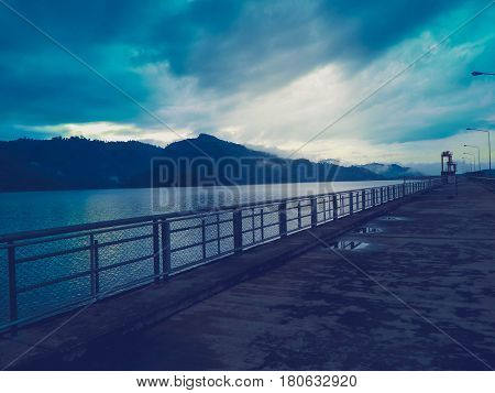 The road in the dam with water, sky and mountain.