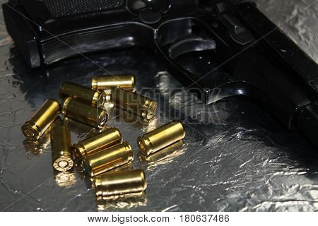 Pistol gun detail with brass golden munition on shiny silver desk