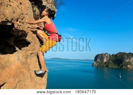 free solo woman rock climber climbing at seaside cliff