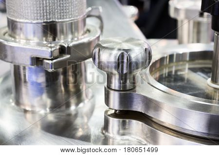 Pharmaceutical equipment, a fragment of the compression lid. Stainless steel. Abstract industrial background.