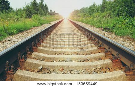 Early morning sun light and train rail road track sleepers. Rural landscape during summer sunrise background. Transportation, perspective industrial concept