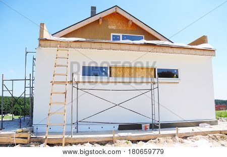 Attic Insulation. Construction or repair of the rural house with insulation eaves windows garage chimney roofing fixing facade plastering. Unfinished house. Insulation House with mineral wool.