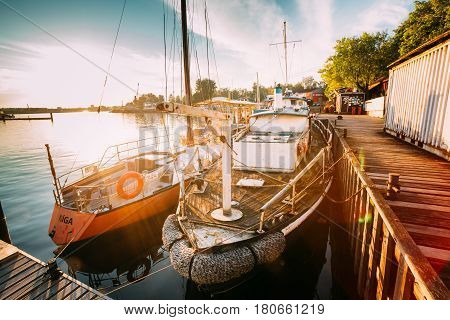 Riga, Latvia - July 1, 2016: Riga, Latvia. Old Boat And Yacht Moored At The City Pier Harbour Bay And Quay In Summer Sunny Evening. Reflections From Boats In Water Of Western Dvina River.