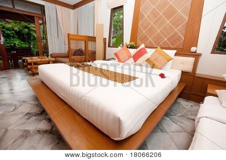 Mooie kingsize bed in de slaapkamer van een tropische hotel.
