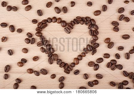 Heart coffee frame made of coffee beans on wooden texture