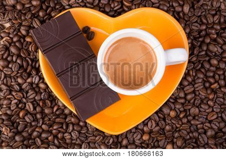 Heart coffee frame made of coffee beans and chocolate on orange plate