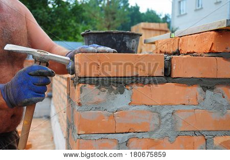 Bricklayer Using a Bricklaying Hammer to Build New Red Brick Wall Outdoor. Bricklaying Basics Masonry Techniques.