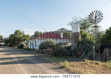 NIEU BETHESDA SOUTH AFRICA - MARCH 22 2017: An early morning street scene with a house and water-pumping windmill in Nieu-Bethesda an historic village in the Eastern Cape Province