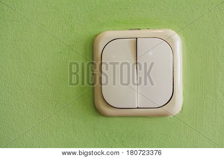 Two keys beige light switch mounted on green wall