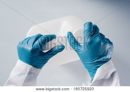 Chemical scientist opening white unlabeled plastic tank canister with chemicals on laboratory table