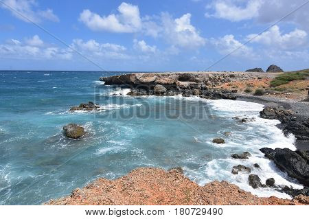 Aqua tropical waters off of Aruba's east coast and the black sand stone beach.