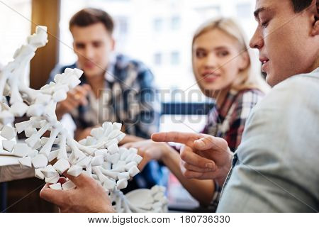 Future scolars. Selective focus of DNA model while cheerful smart students discussing project and studying genetics