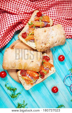 sandwich with smoked salmon on blue wooden table.