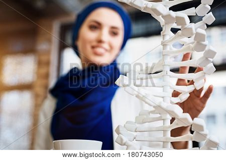 New prospective. Selective focus of DNA model with muslim woman learnign it in the background