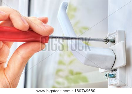 Hand unscrews the bolt using a screwdriver uninstall window handle.