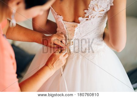 Mom button up the bride's dress. Dressing up a wedding dress.
