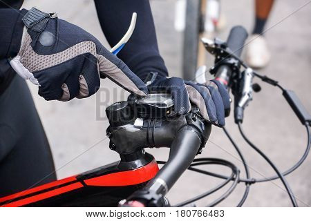 A mountain bike cyclist adjusting bike computer installed on a bicycle's handlebar