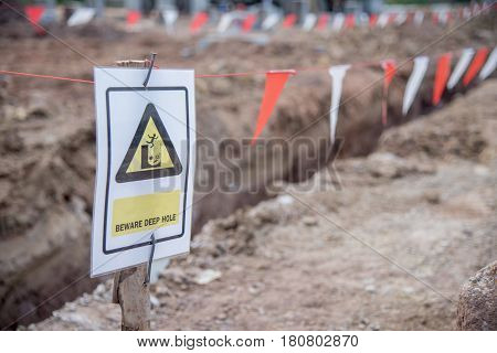 Beware deep hole warning sign and white red flag safety in construction site
