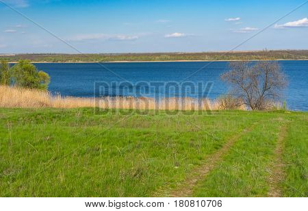 Early spring landscape with an earth road leading to Dniepr river in central Ukraine