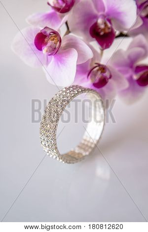 Zirconium bracelet lies on the background of purple orchids