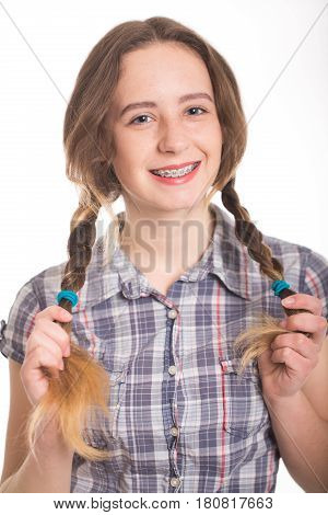 A cute piggy girl in a checkered shirt shows her braces. Isolated on white. Dental concept