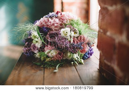 Tenderless bouquet with bow and ribbons in green and pink and blue colours on brown background