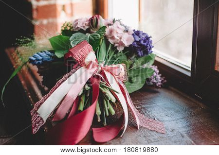 Tenderless bouquet with bow and ribbons in green and pink and blue colours on brown background