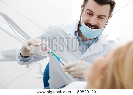 Just in case you didnt know. Attractive skillful competent doctor explaining special techniques for teeth cleaning to his patient using some tools